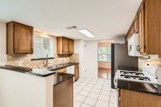Kitchen featuring visible vents, brown cabinetry, light tile patterned floors, and white appliances | Image 8