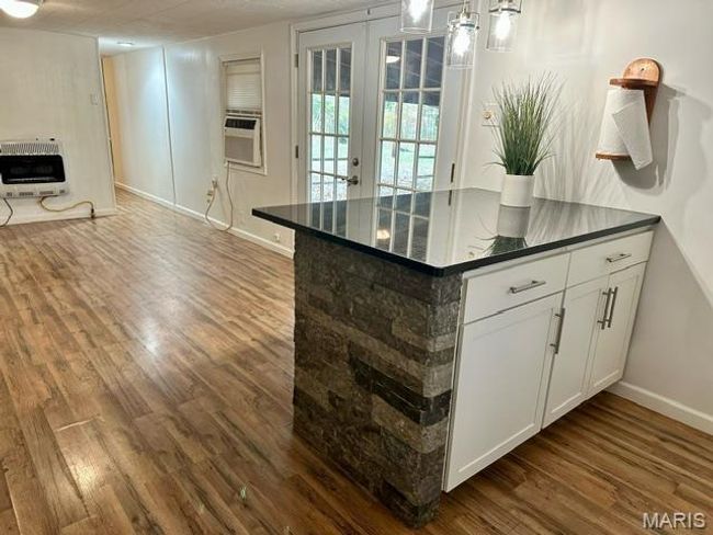 Kitchen with dark wood-type flooring, french doors, white cabinets, cooling unit, and heating unit | Image 21