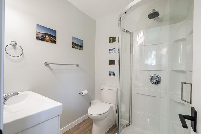 Full bathroom featuring a stall shower, wood finished floors, baseboards, toilet, and vanity | Image 29