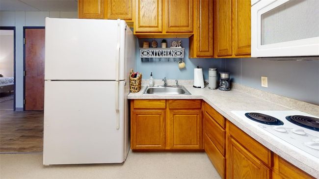 Kitchen featuring white appliances, a sink, light countertops, and brown cabinets | Image 42