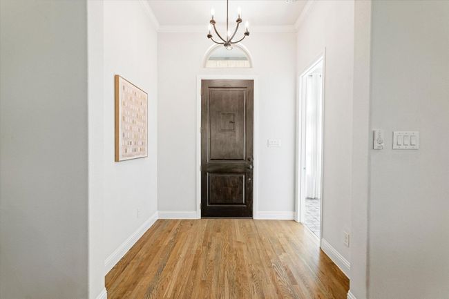 Entryway featuring light wood finished floors, a chandelier, and ornamental molding | Image 4