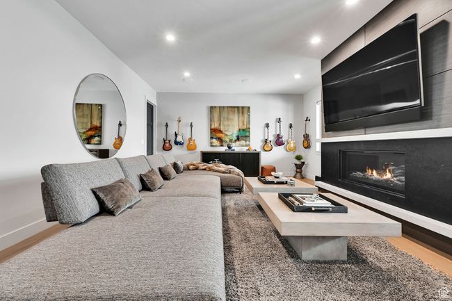 Living area featuring recessed lighting, a glass covered fireplace, wood finished floors, and baseboards | Image 38