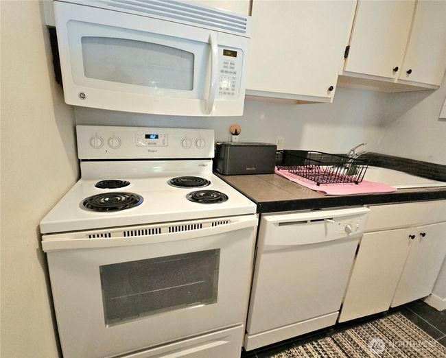 which includes crisp, white appliances and cabinets. | Image 8