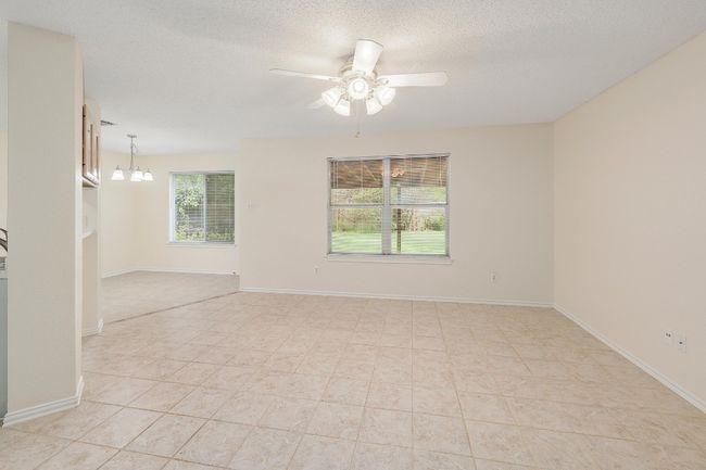 Unfurnished room featuring a ceiling fan, a textured ceiling, a chandelier, light tile patterned floors, and baseboards | Image 4