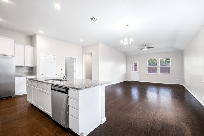 Kitchen featuring appliances with stainless steel finishes, a chandelier, open floor plan, dark wood finished floors, and light stone countertops | Image 12
