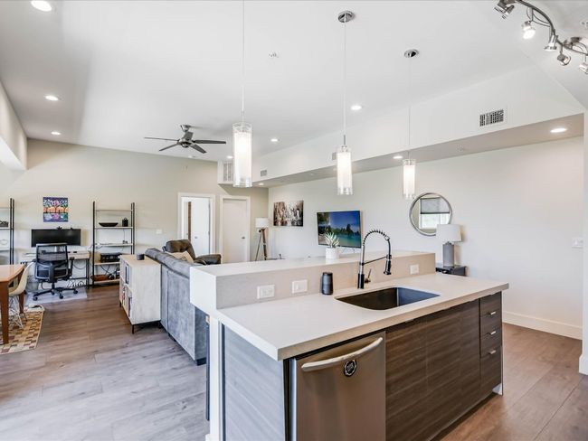 Kitchen featuring stainless steel dishwasher, open floor plan, a ceiling fan, light wood-style flooring, and light countertops | Image 14