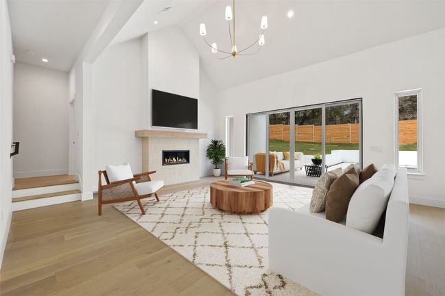 Living room featuring high vaulted ceiling, a chandelier, wood finished floors, a tile fireplace, and recessed lighting | Image 7