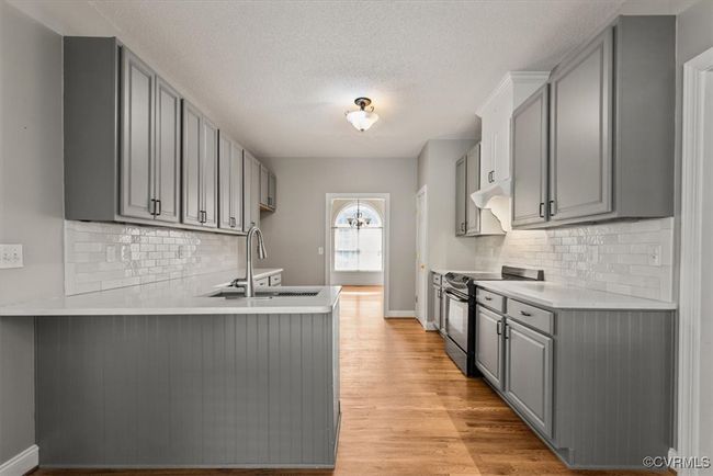 Kitchen featuring electric stove, gray cabinets, a peninsula, a sink, and light countertops | Image 12