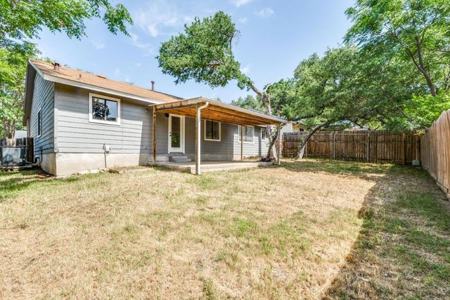 Rear view of house with a lawn, a fenced backyard, central AC, and a patio area | Image 23