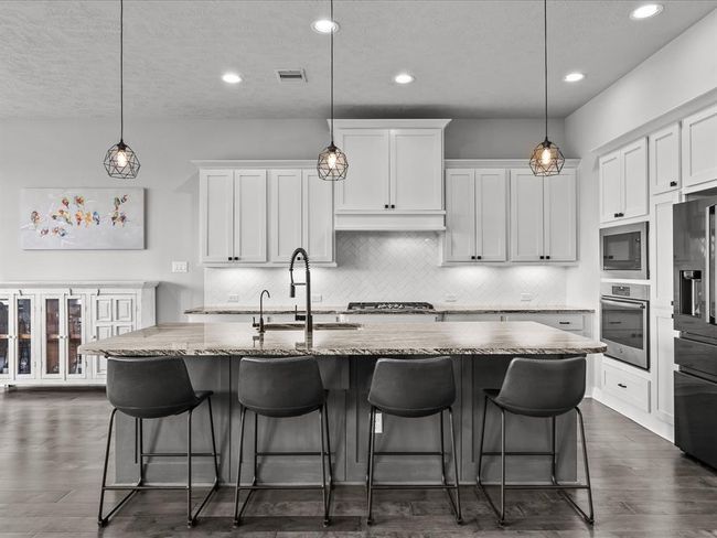Chef's eat-in island kitchen features 42" cabinets with crown molding, under cabinet lighting, designer backsplash, stainless steel appliances and legthy countertops | Image 6