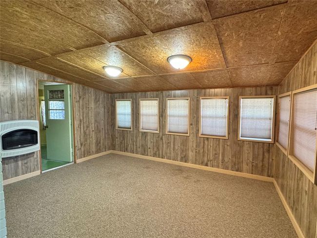Unfurnished room with a healthy amount of sunlight, wooden walls, and carpet flooring | Image 16