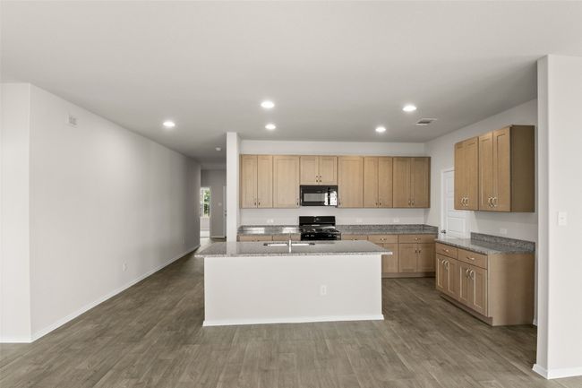 Kitchen with baseboards, recessed lighting, a kitchen island with sink, dark wood-type flooring, and black appliances | Image 5