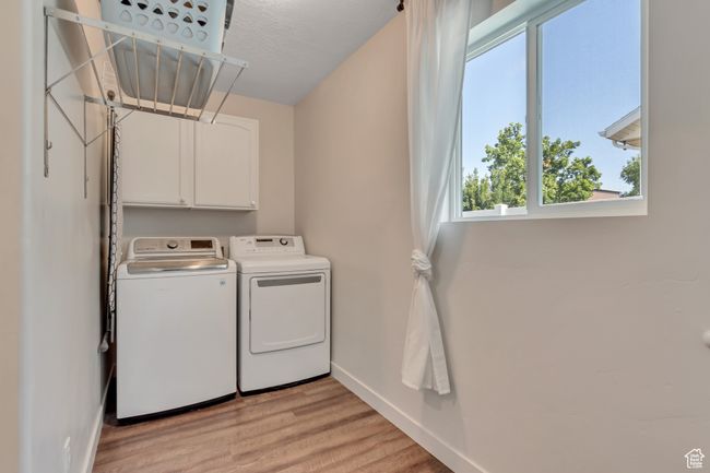 Laundry area with separate washer and dryer, light wood finished floors, and cabinet space | Image 19