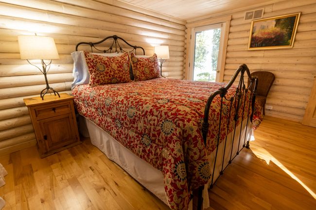 Bedroom featuring light hardwood / wood-style floors, wooden ceiling, and rustic walls | Image 31