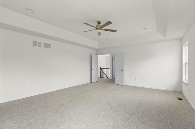 Unfurnished room featuring carpet, a tray ceiling, and ceiling fan | Image 7