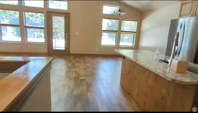 Kitchen featuring plenty of natural light, light wood finished floors, baseboards, and lofted ceiling | Image 19
