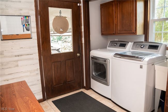 Laundry area with cabinet space, washing machine and clothes dryer, and light tile patterned flooring | Image 28
