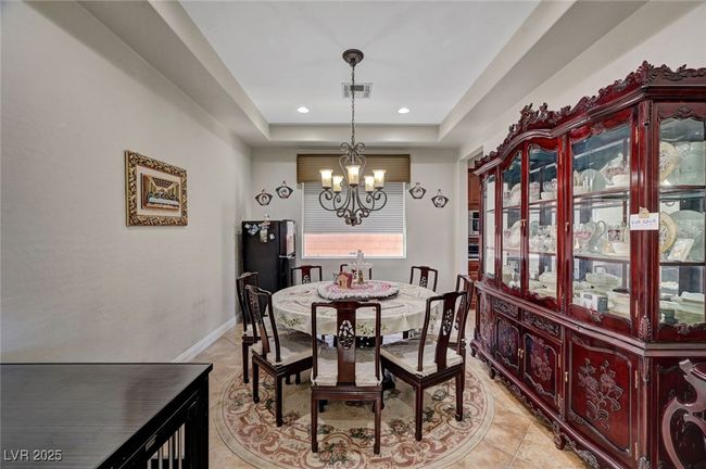 Dining room with a chandelier, a tray ceiling, light tile patterned floors, and recessed lighting | Image 23