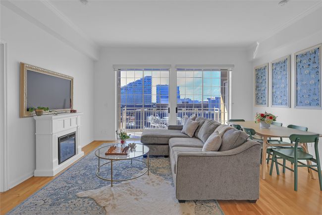 Living area featuring light wood-type flooring, a glass covered fireplace, and crown molding | Image 6
