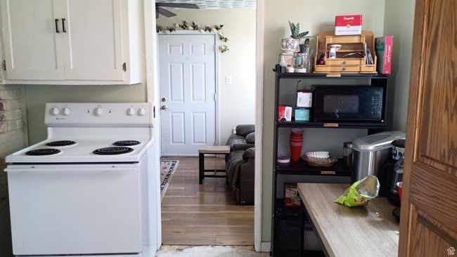Kitchen with white electric stove, white cabinets and light wood-style flooring. | Image 32