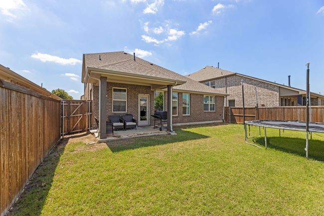Back of house featuring brick siding, a trampoline, a fenced backyard, and a patio area | Image 38