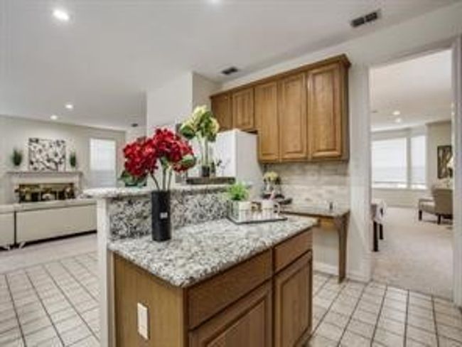Kitchen featuring brown cabinets, light tile patterned flooring, plenty of natural light, backsplash, and recessed lighting | Image 11