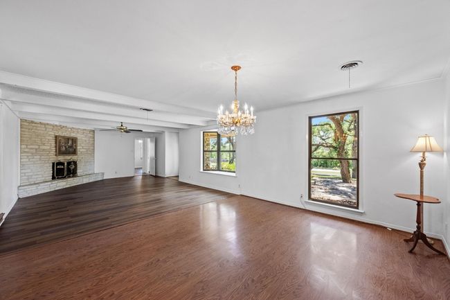 Unfurnished living room with a brick fireplace, dark wood-type flooring, a ceiling fan, and a chandelier | Image 4