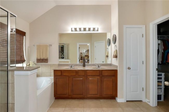 Full bathroom with double vanity, tile patterned floors, a walk in closet, a bath, and vaulted ceiling | Image 14