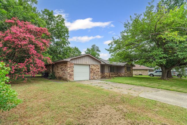 View of front of house with brick siding, a garage, a front yard, driveway, and board and batten siding | Image 28
