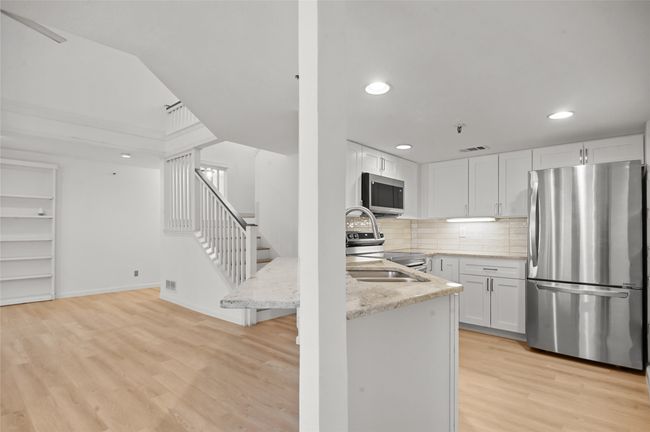Kitchen featuring stainless steel appliances, light stone countertops, light wood-type flooring, recessed lighting, and white cabinetry | Image 11