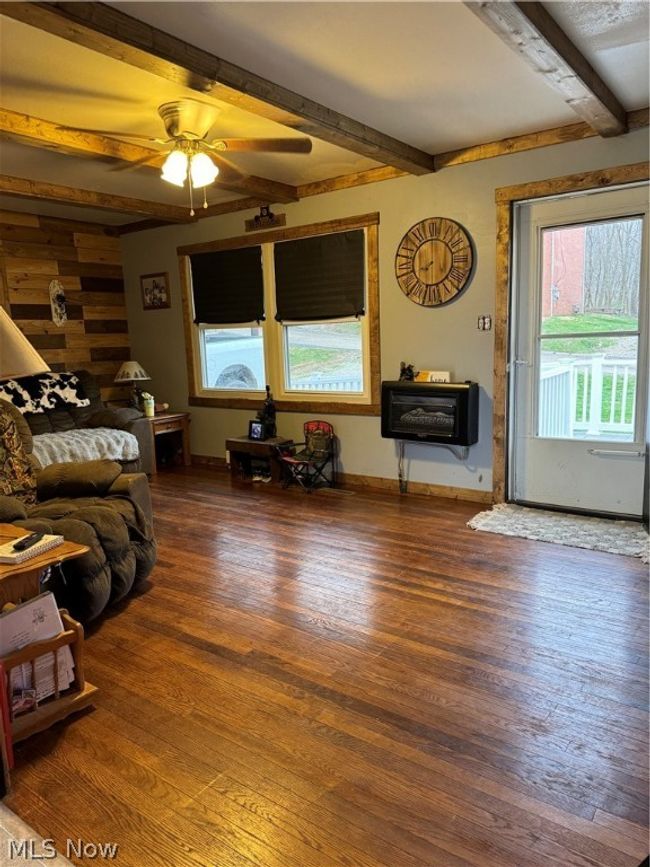 Living room with beam ceiling, a wealth of natural light, dark wood-type flooring, and ceiling fan | Image 2