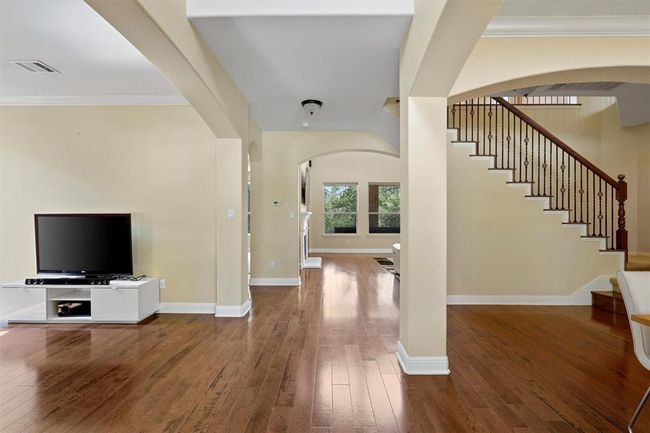 Foyer entrance with arched walkways, wood-type flooring, stairs, baseboards, and crown molding | Image 6