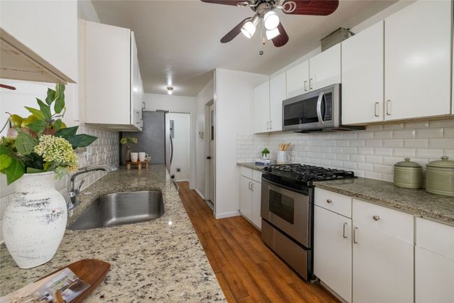 Kitchen featuring stainless steel appliances, a sink, ceiling fan, and tasteful backsplash | Image 4