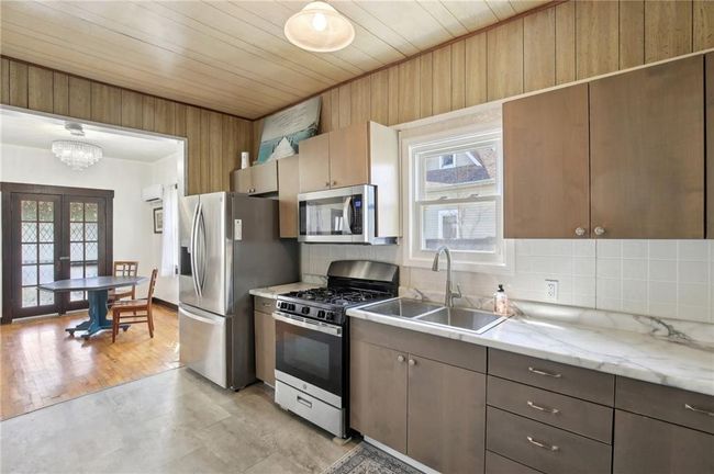 Kitchen with appliances with stainless steel finishes, wood ceiling, decorative backsplash, and a sink | Image 10