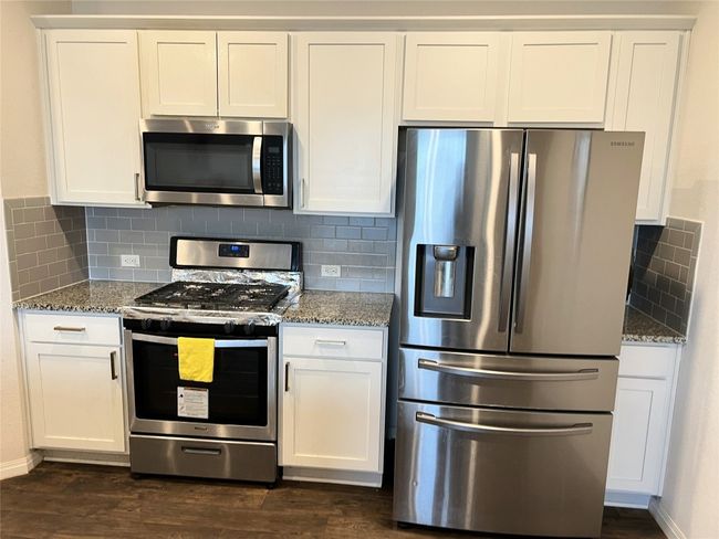 Kitchen with stainless steel appliances, stone counters, and dark wood finished floors | Image 8