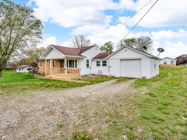 view of front of house featuring a garage, a porch, dirt driveway, and a front yard | Image 35