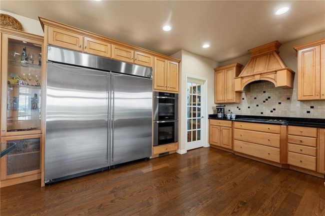Kitchen with appliances with stainless steel finishes, dark wood-type flooring, light brown cabinets, and custom range hood | Image 17