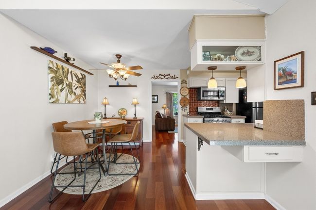 Kitchen featuring a peninsula, white cabinetry, stainless steel appliances, dark wood-type flooring, and decorative backsplash | Image 9