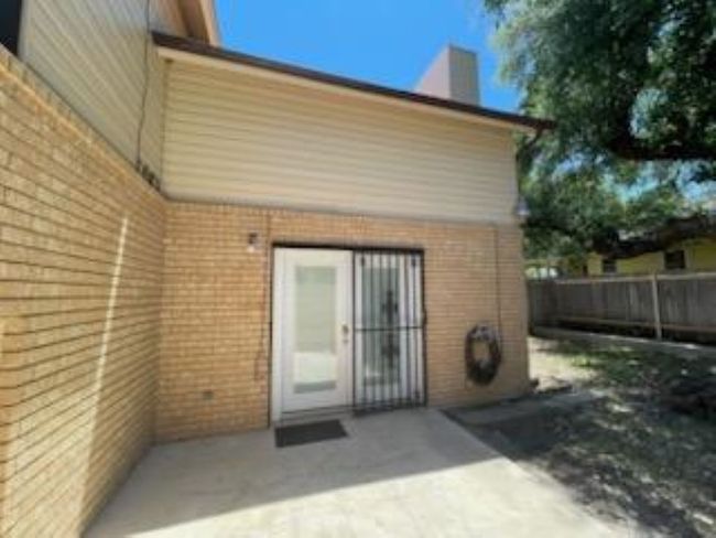 Back of house featuring brick siding, a chimney, fence, and a patio area | Image 7
