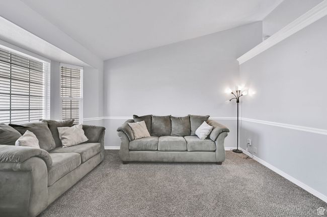 Carpeted living area featuring baseboards and vaulted ceiling | Image 5