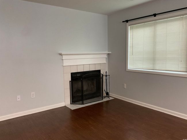Unfurnished living room featuring wood finished floors and a tiled fireplace | Image 5