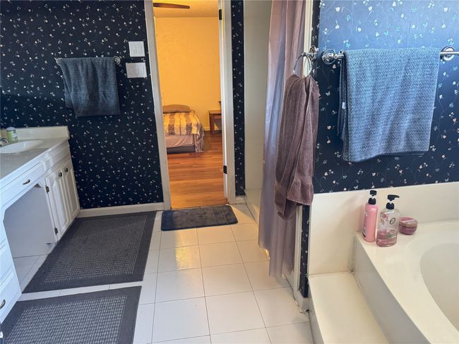 Bathroom with tile patterned flooring, vanity, and a tub to relax in | Image 19
