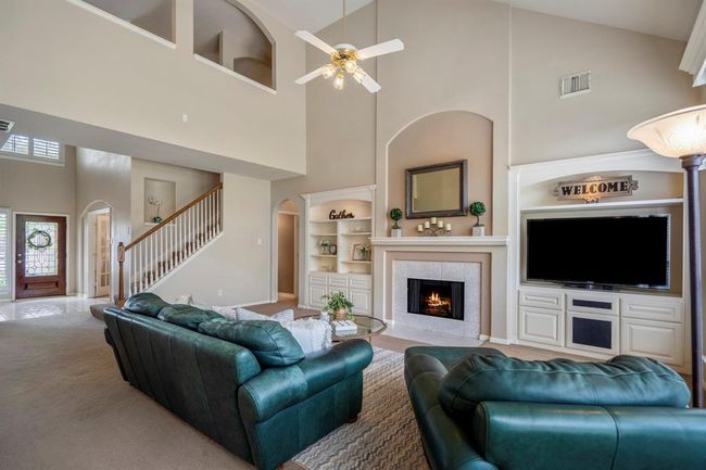 As you move towards the breakfast nook, looking back at the family room, the front door is visible on the left. Just to the right of the stairs, an open door through the archway leads to the primary suite and the half bath under the stairs. This angle offers another clear view of the gas-started fireplace, framed by built-ins on both sides, creating a focal point in the room. | Image 11