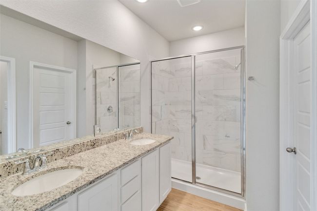 Full bathroom with double vanity, a shower stall, a sink, and wood finished floors | Image 31