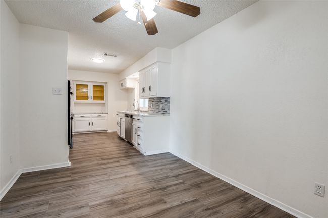 Kitchen with dishwasher, a textured ceiling, white cabinets, a ceiling fan, and dark wood finished floors | Image 10