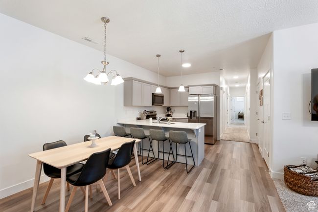 Kitchen with appliances with stainless steel finishes, a peninsula, light countertops, a kitchen breakfast bar, and a chandelier | Image 4