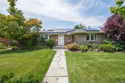 Ranch-style house with solar panels and a front yard | Image 1