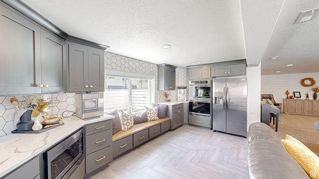 Kitchen with a textured ceiling, light stone countertops, gray cabinets, and appliances with stainless steel finishes | Image 24