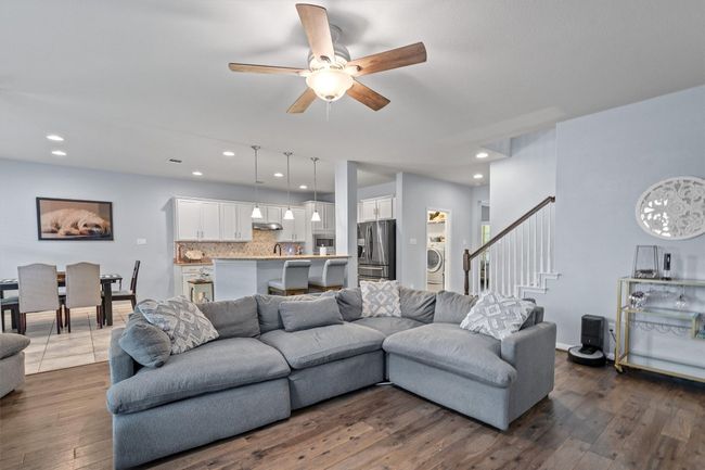 Living room featuring a ceiling fan, dark wood finished floors, stairway, washer / dryer, and recessed lighting | Image 11