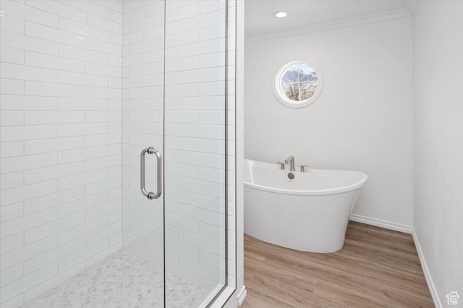 Bathroom featuring crown molding, baseboards, a shower stall, a freestanding bath, and wood finished floors | Image 20